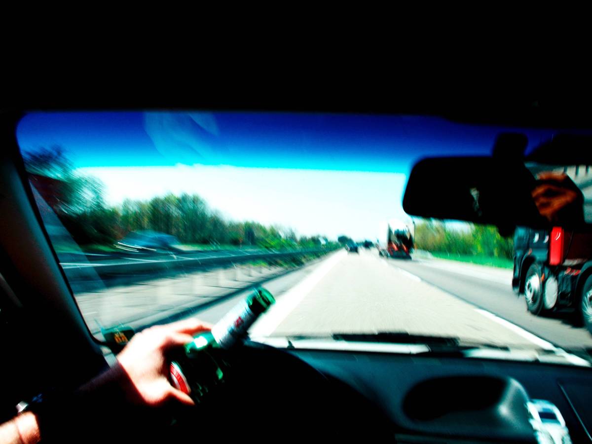 Blick aus Auto auf Autobahn mit Bierflasche am Steuer