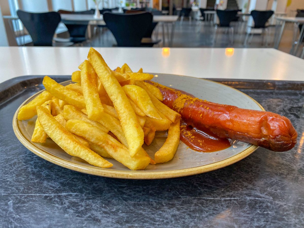 Currywurst Pommes auf Teller in einer Kantine