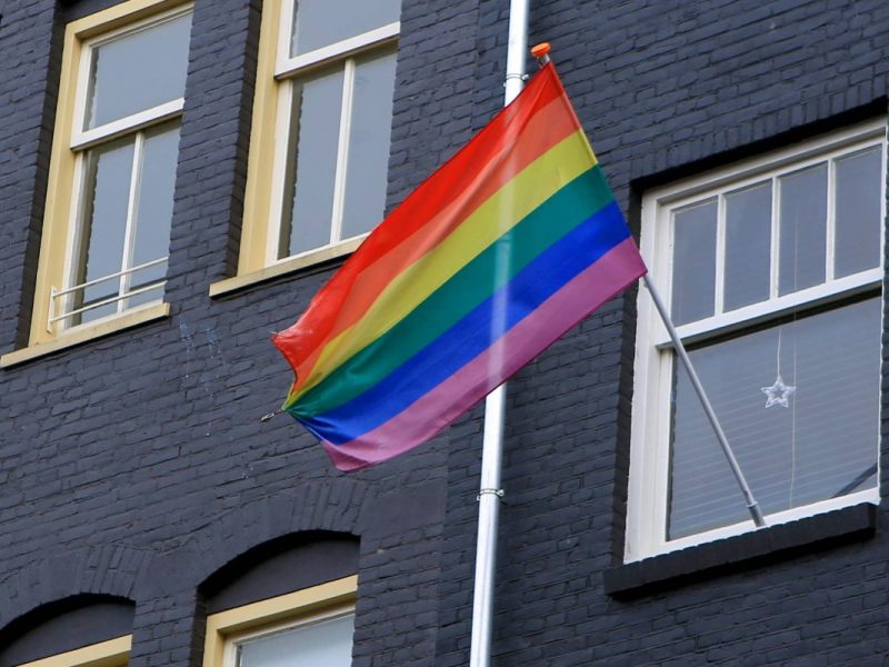 Eine Regenbogenfahne weht an einem haus.