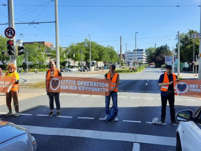 Aktivisten der letzten Generation stehen auf einer Straße in Braunschweig und blockieren den Verkehr