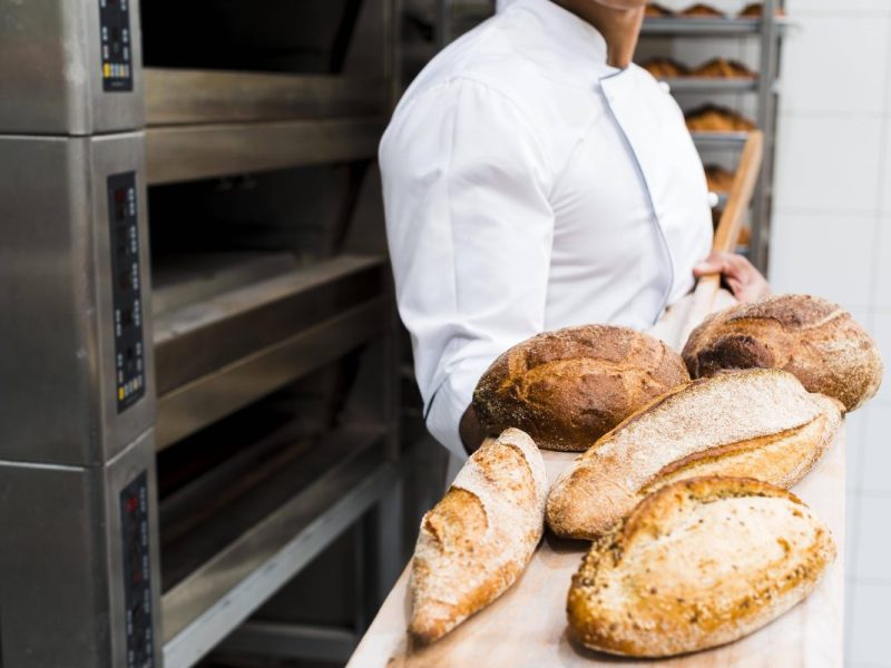 Bäcker hält frisches Brot auf einer Schaufel in die Kamera