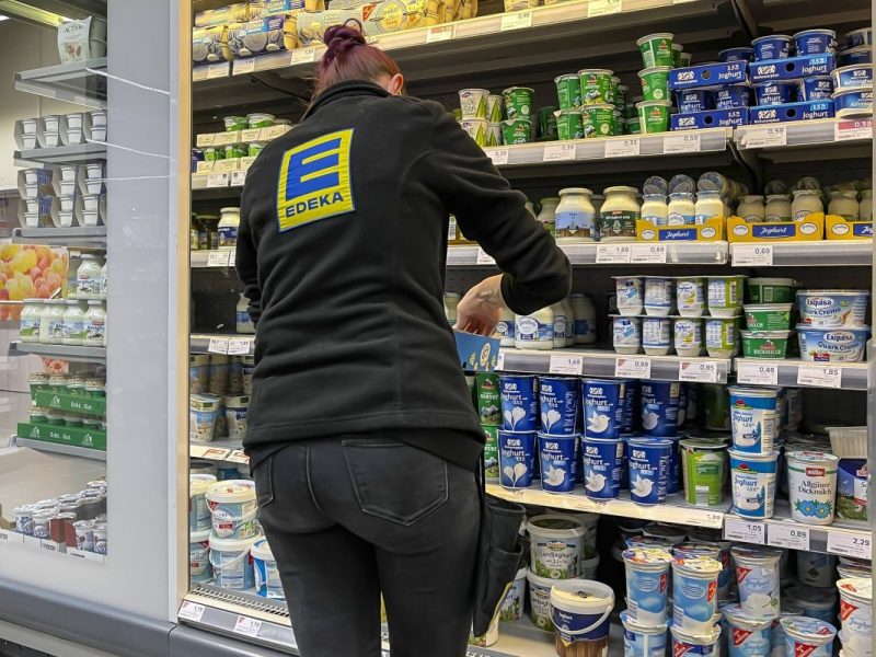 Mitarbeiterin in einem Edeka Markt räumt Waren ein