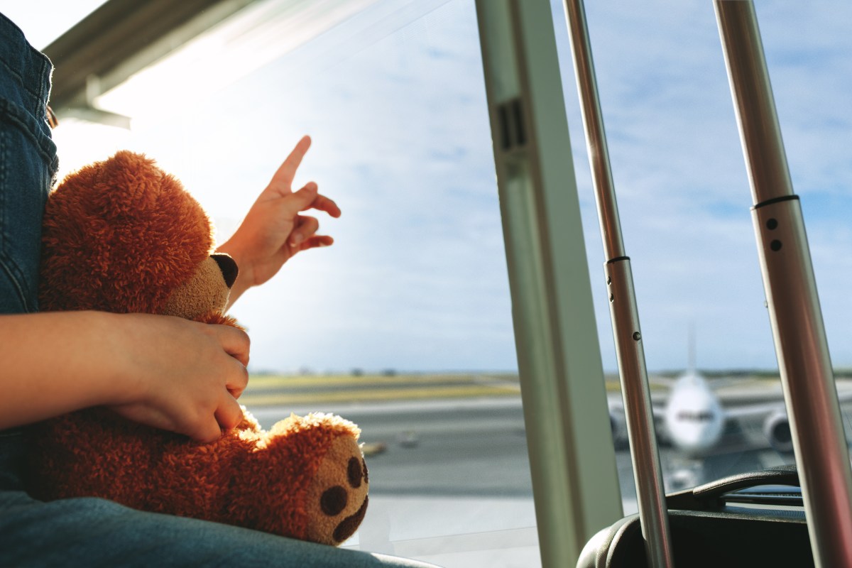 finger pointing towards the sky and showing the plane while waiting at airport terminal.