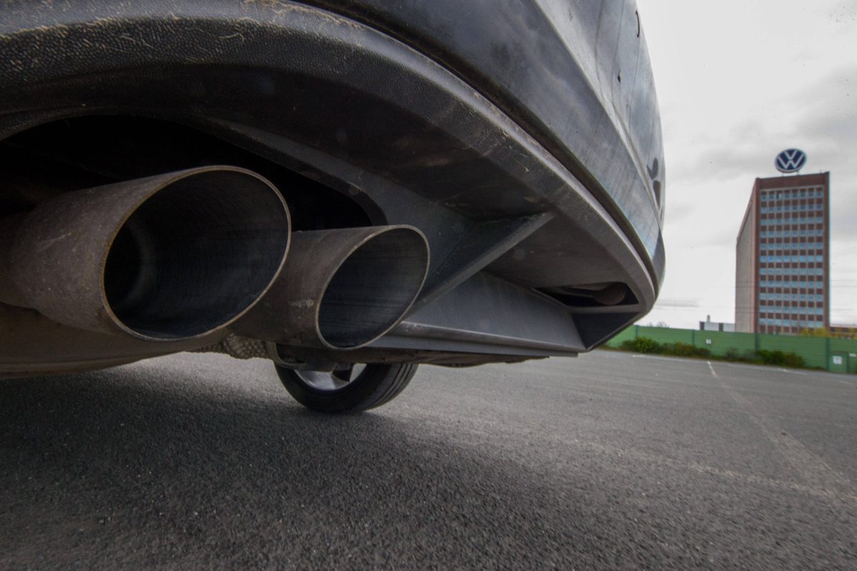 Auspuff eines Autos vor dem Hintergrund des VW-Markenhochhauses in Wolfsburg