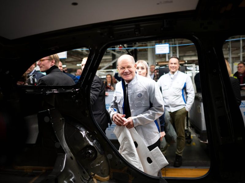 Bundeskanzler Olaf Scholz (SPD) legt im VW-Werk Emden eine Dämmmatte in einen Wagen.